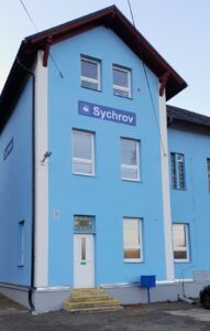 Úvodní foto - nádražní budova s cedulí Sychrov